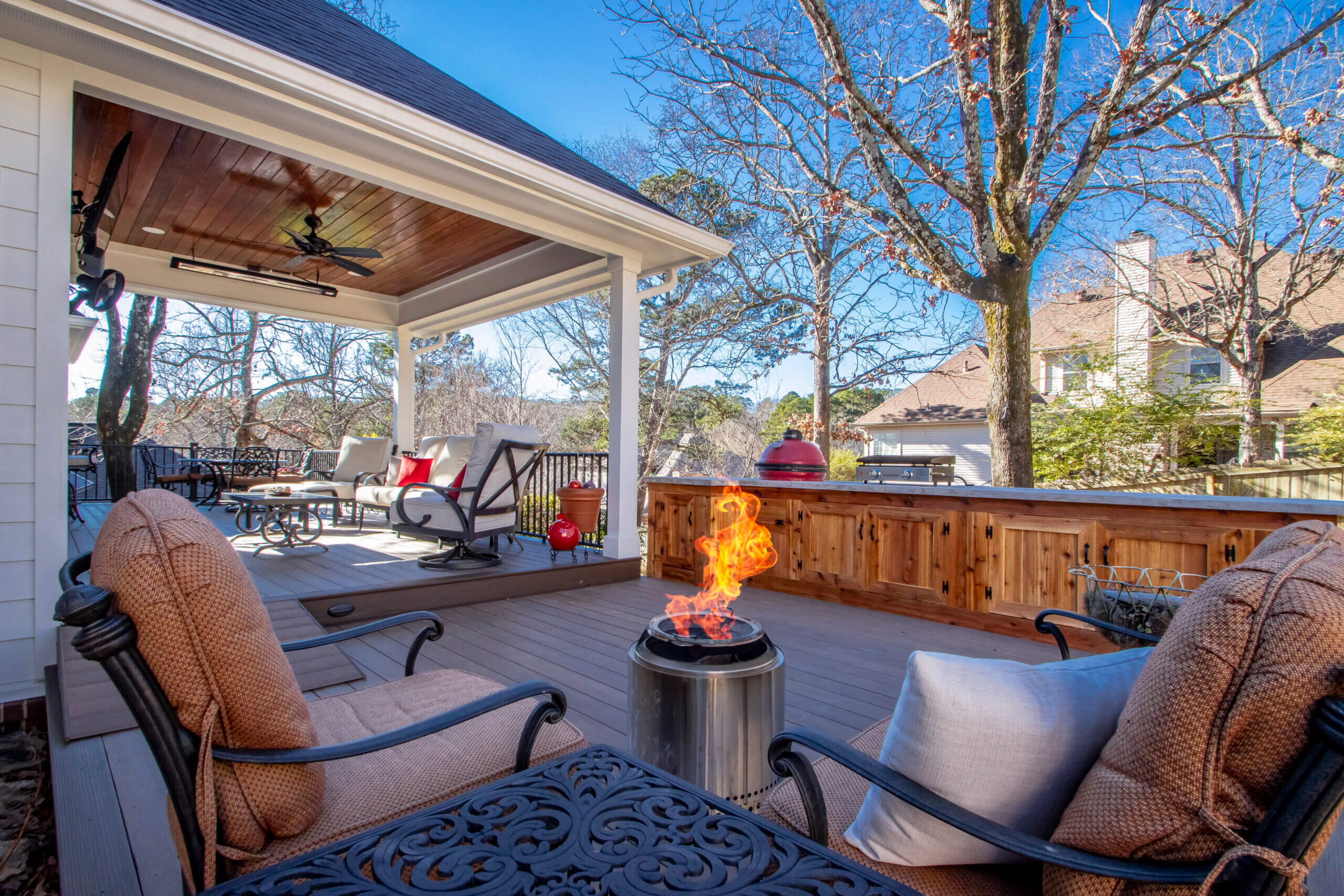 Two level back porch with deep brown timbertech, a built in kitchen with cement top, and a fire pit